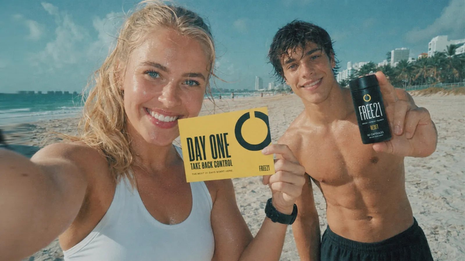 Two people on the beach holding the FREE21 Day One card and a RESET bottle